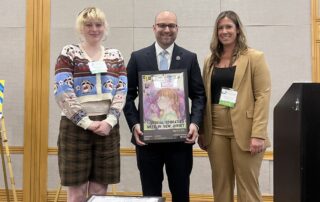 Special Education Week Grand Prize Winner Catherine M. of Holmstead School in Ridgewood poses alongside her award-winning artwork, held by New Jersey Department of Education Commissioner Kevin Dehmer joined with ASAH External Affairs Director Stephanie Summers.